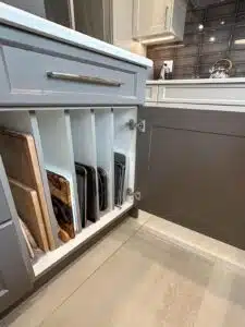 A kitchen cabinet with cutting boards in it

Description automatically generated